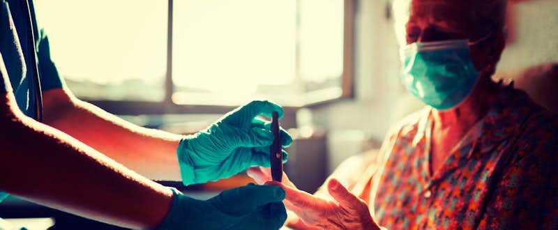 A close up of a health professional's gloved hands as they interact with a patient.
