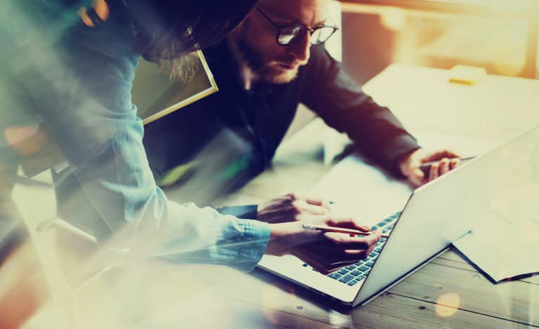 Employees discuss materials on a laptop screen