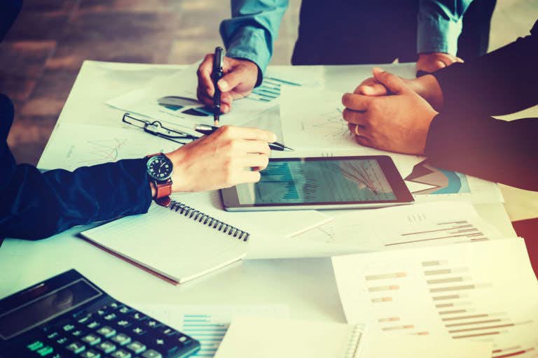 Photo of meeting with a close up on hands, materials and ipad