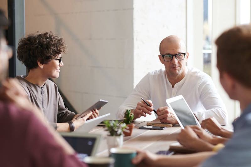 Individuals gather for a meeting around a table